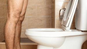 Homem diante do vaso sanitário com dificuldades para iniciar a micção, pensando em problemas na próstata