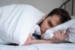 Homem com dificuldades para dormir, pensando se urinar várias vezes à noite é normal