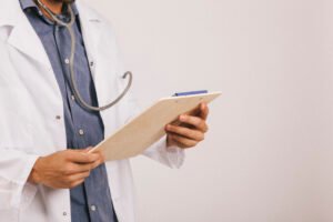 Médico com uma prancheta na mão, explicando qual a diferença entre HPB e câncer de próstata.