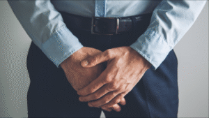 Homem elegante com as mãos na região genital, com dificuldades para urinar