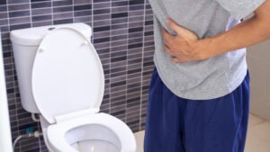 Homem no banheiro, pensando em como o HoLEP evita complicações urinárias